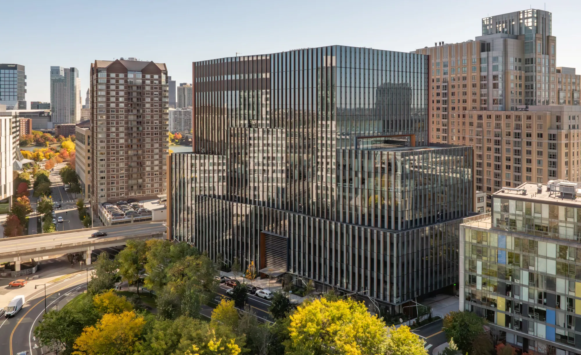 Modern office building with glass facade surrounded by high rise apartments and tree lined city streets