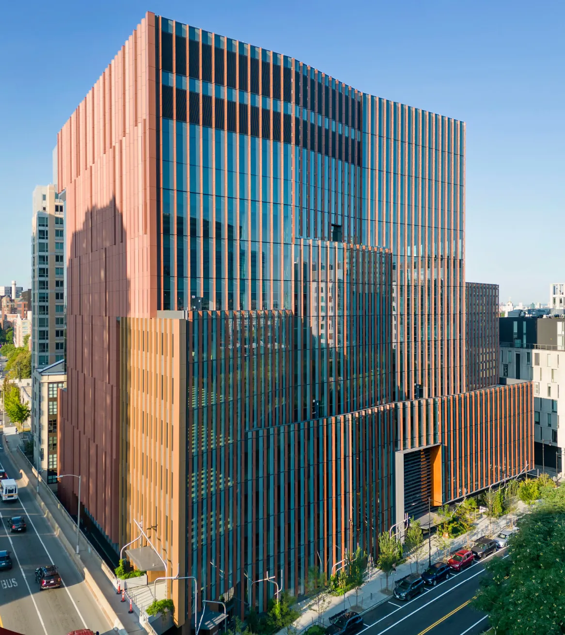 Contemporary commercial architecture featuring reflective glass facade and bronze vertical panels in downtown environment