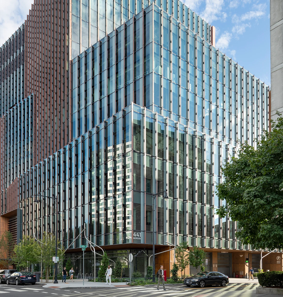 Modern commercial building with transparent facade and vertical metal accents along active city intersection