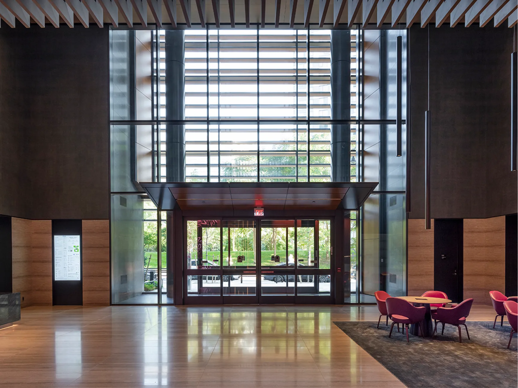 Contemporary building lobby with wood finishes glass walls and lounge seating near main entrance doors