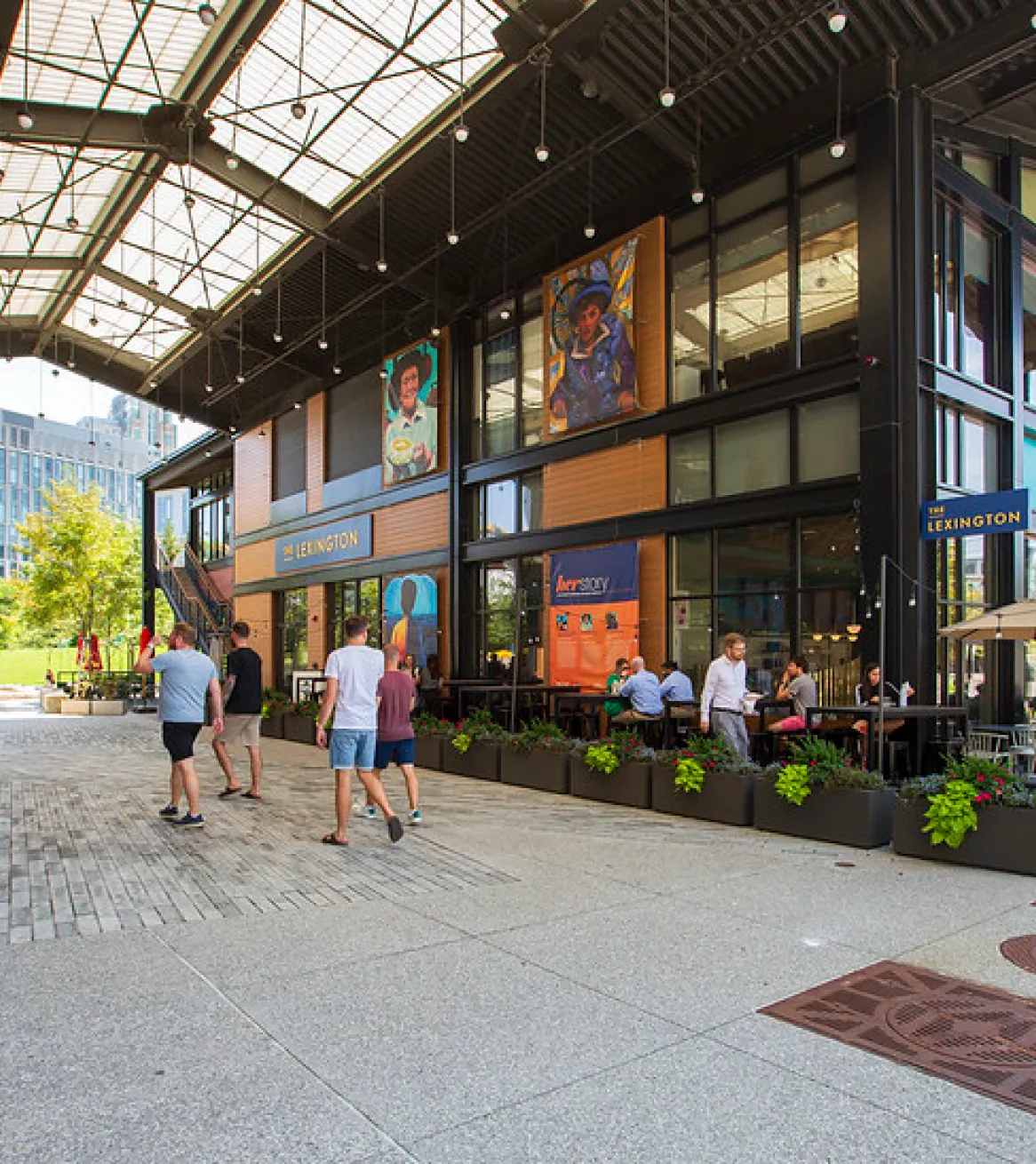 Cambridge Crossing retail pavilion with outdoor dining seating colorful murals and people walking through plaza