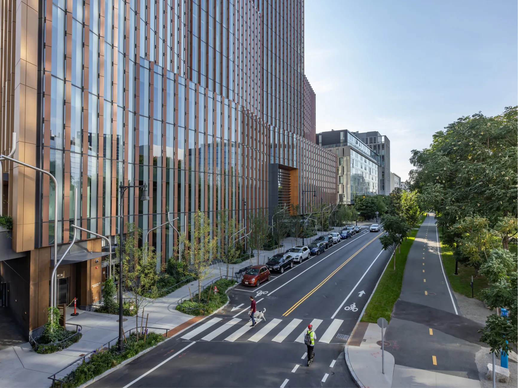 Elevated view of modern glass office building along tree lined Cambridge street with crosswalk and bike lane